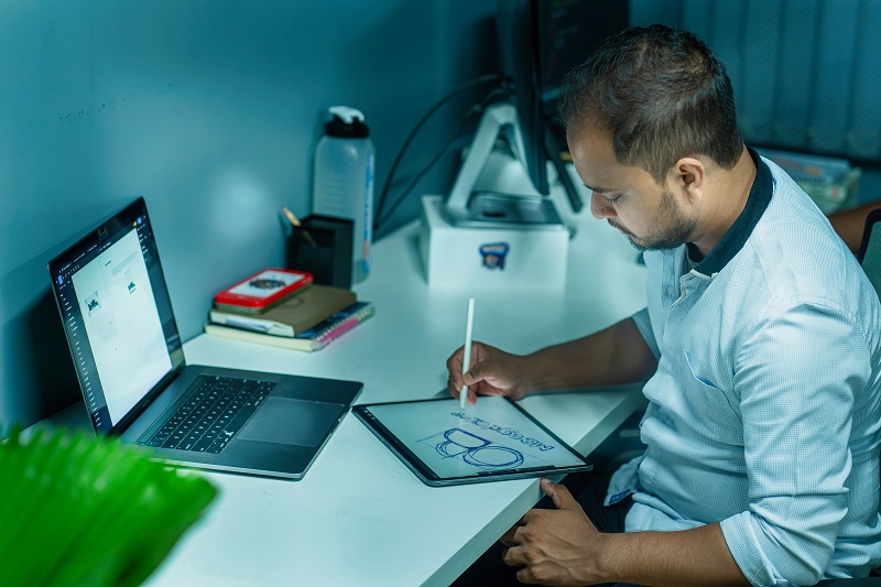 Graphic designer sketching a website layout on a tablet while transitioning into web design.